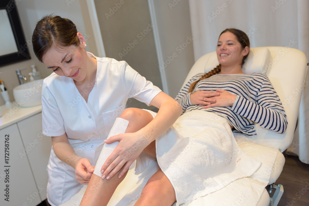 Obraz premium beautician epilating womans leg at salon