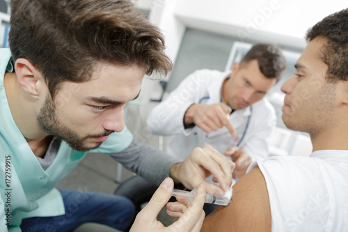 close-up of doctor injecting patient with syringe to collect blood