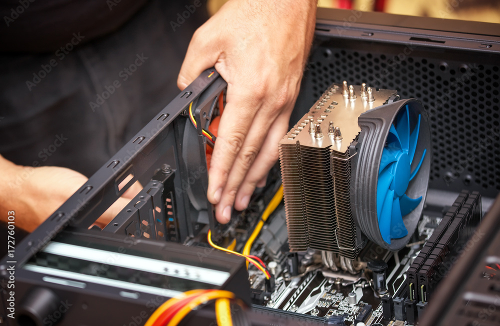 Computer technician installs cooling system of computer. Assembling PC