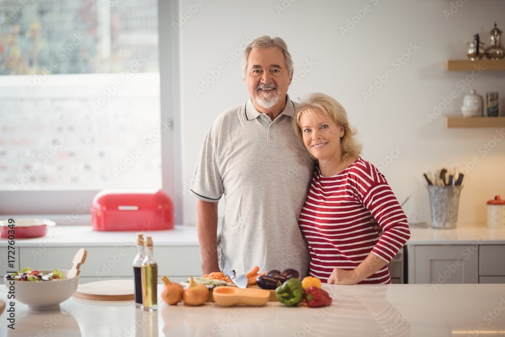 Smiling senior couple standing together in kitchen Smiling senior couple standing together in kitchen
