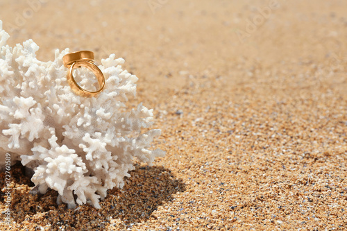 Golden rings on coral at seaside. Wedding on beach concept