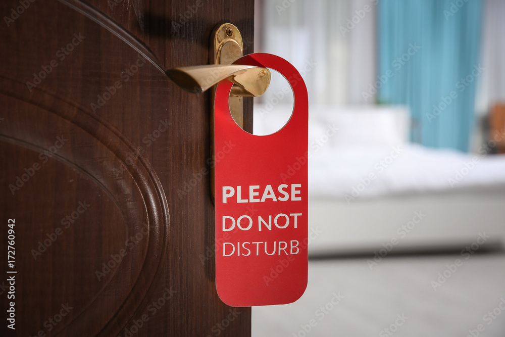 Fototapeta premium Open door with sign PLEASE DO NOT DISTURB on handle at hotel