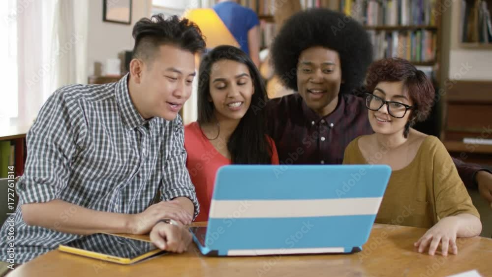 Happy group of student friends making a video call on computer in shared accommodation. Happy group of student friends making a video call on computer in shared accommodation.
