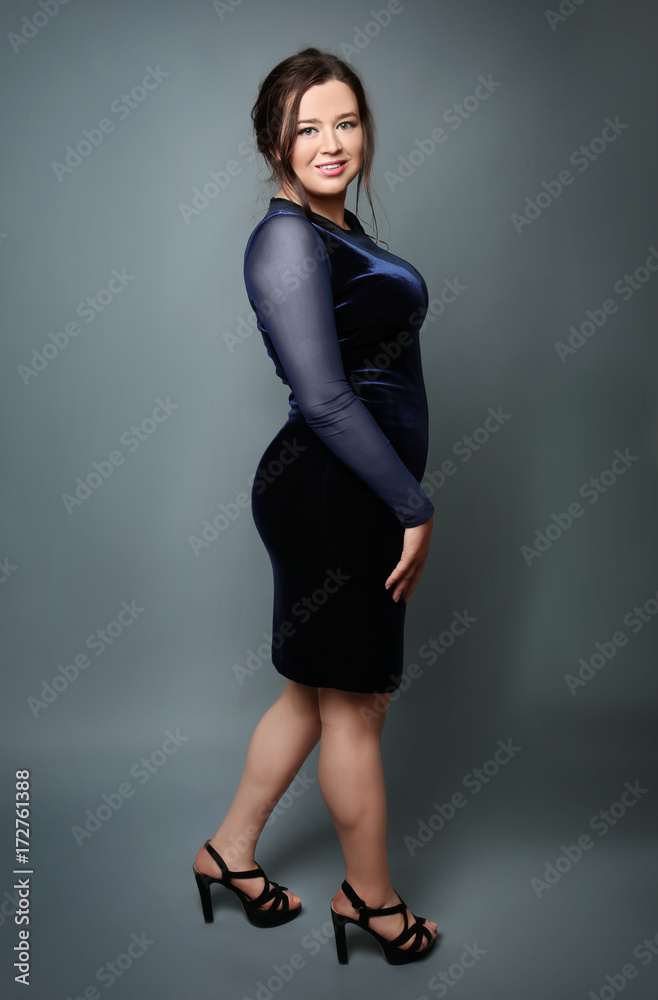 Beautiful overweight woman in dress on grey background Beautiful overweight woman in dress on grey background