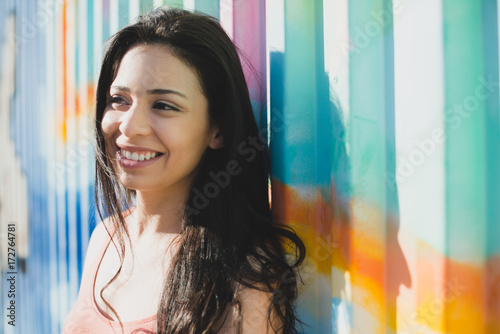 Young woman smiling and standing against colorful graffiti wall photo