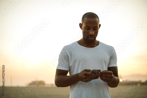 Young handsome black man looking at his phone