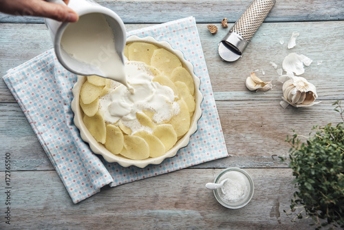 Food: Prearing gratinated potatos, pouring cream onto potatos photo