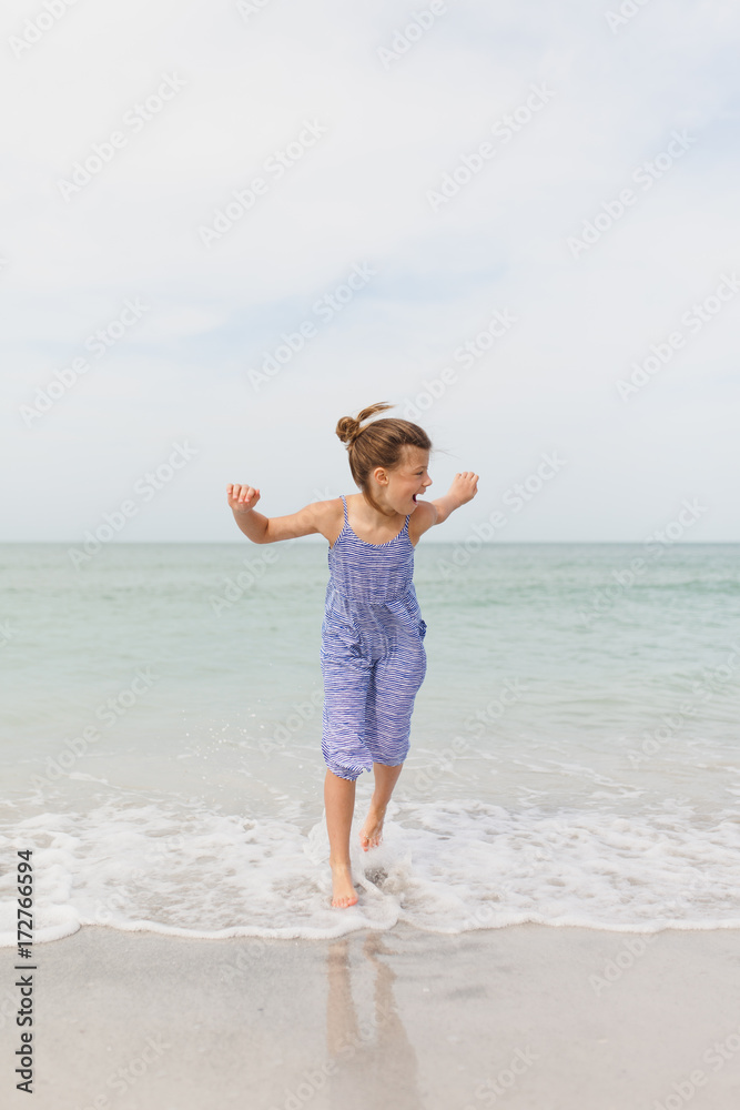 Preteen girl laughing while running in the ocean Preteen girl laughing while running in the ocean