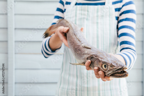 Woman fishmonger holding a large Hake photo