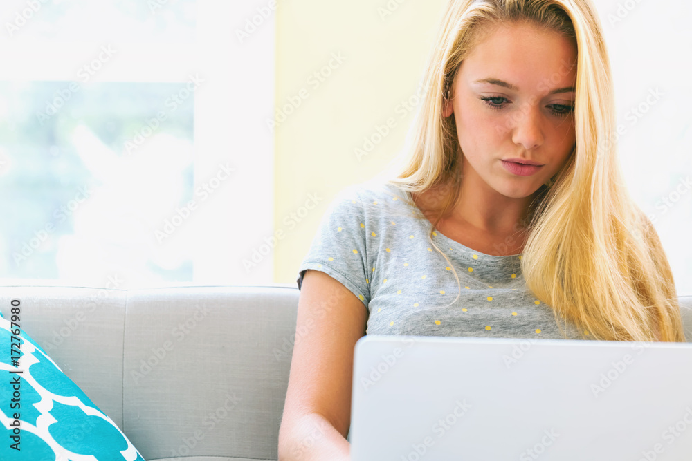 Young woman using her laptop in on her couch in her living room Young woman using her laptop in on her couch in her living room