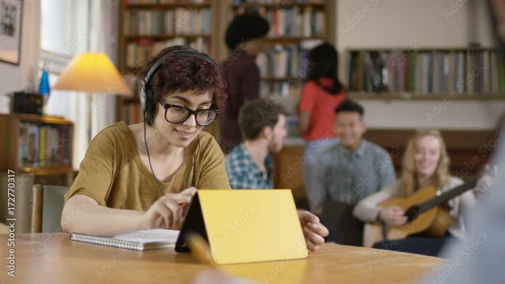Student in shared accommodation trying to concentrate on work while others socialize in background. Student in shared accommodation trying to concentrate on work while others socialize in background.
