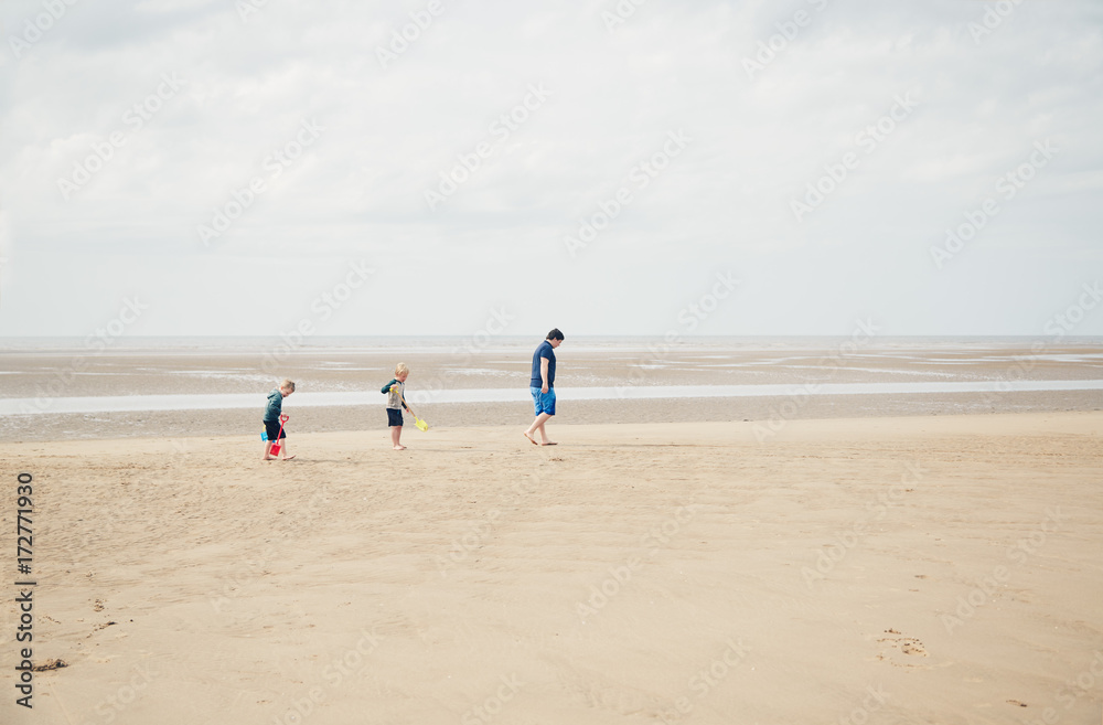 Father and two sons walking on the beach together Father and two sons walking on the beach together