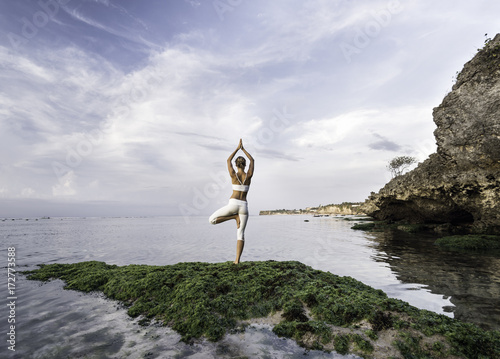 woman practicing yoga at sea shore