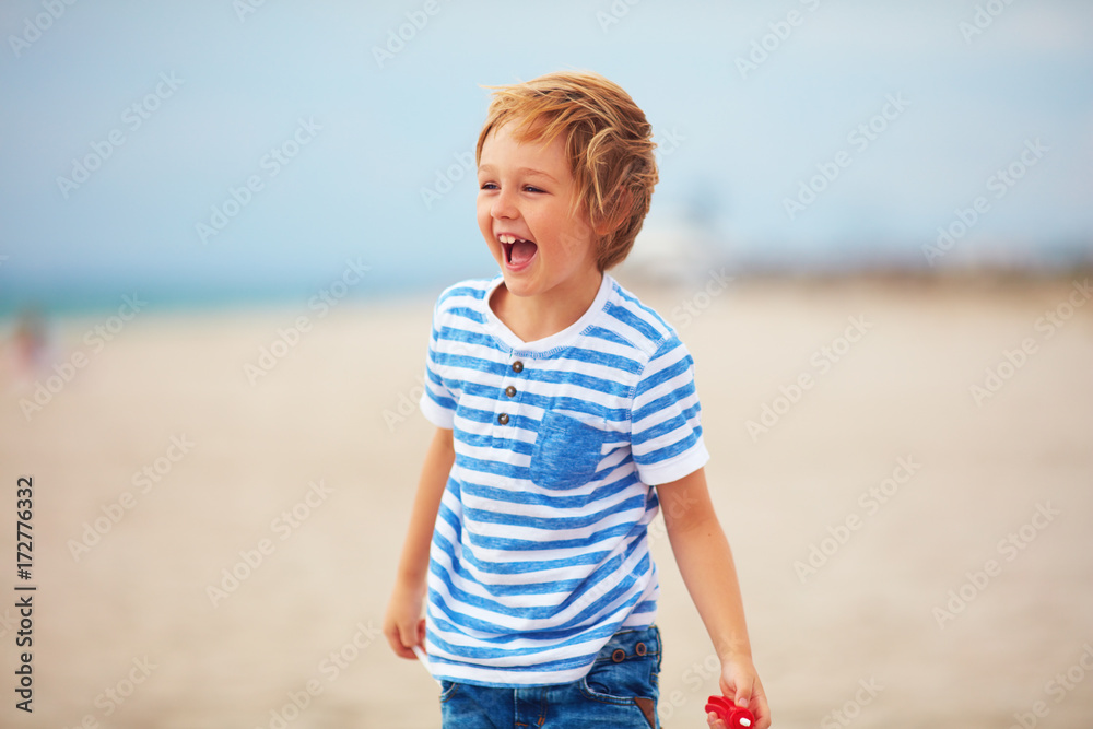 young delighted boy, kid playing with a toy propeller, having fun on summer beach young delighted boy, kid playing with a toy propeller, having fun on summer beach