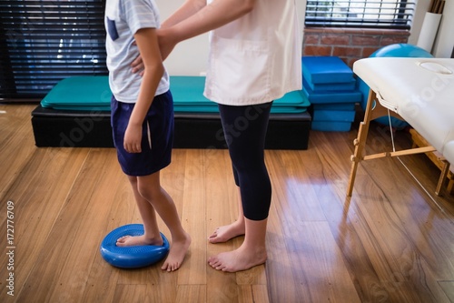 Low section female therapist holding boy standing on blue stress