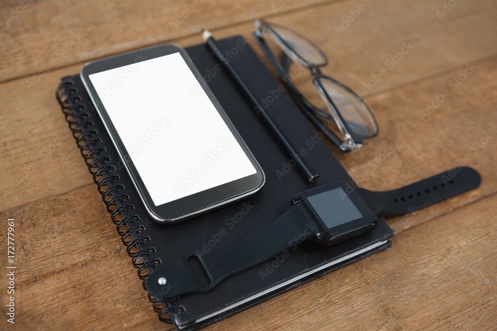 Diary, smart watch, pencil, smartphone and spectacles Diary, smart watch, pencil, smartphone and spectacles