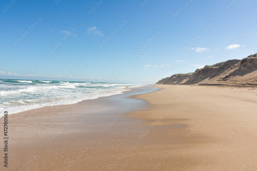 Long deserted beach with large sand dunes on sunny day in Coorong National Park, South Australia