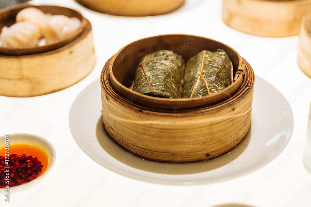 Dim Sum: Sticky rice with shrimp and wrap with lotus leaves in bamboo basket at the restaurant in Dubai. Dim Sum: Sticky rice with shrimp and wrap with lotus leaves in bamboo basket at the restaurant in Dubai.