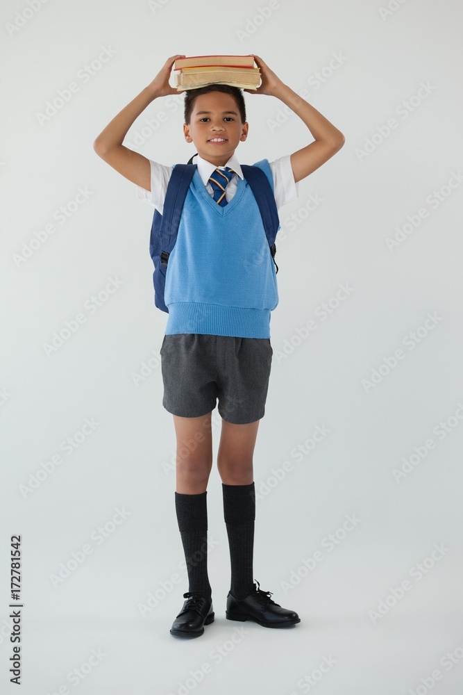 Schoolboy holding books on his head against white background Schoolboy holding books on his head against white background