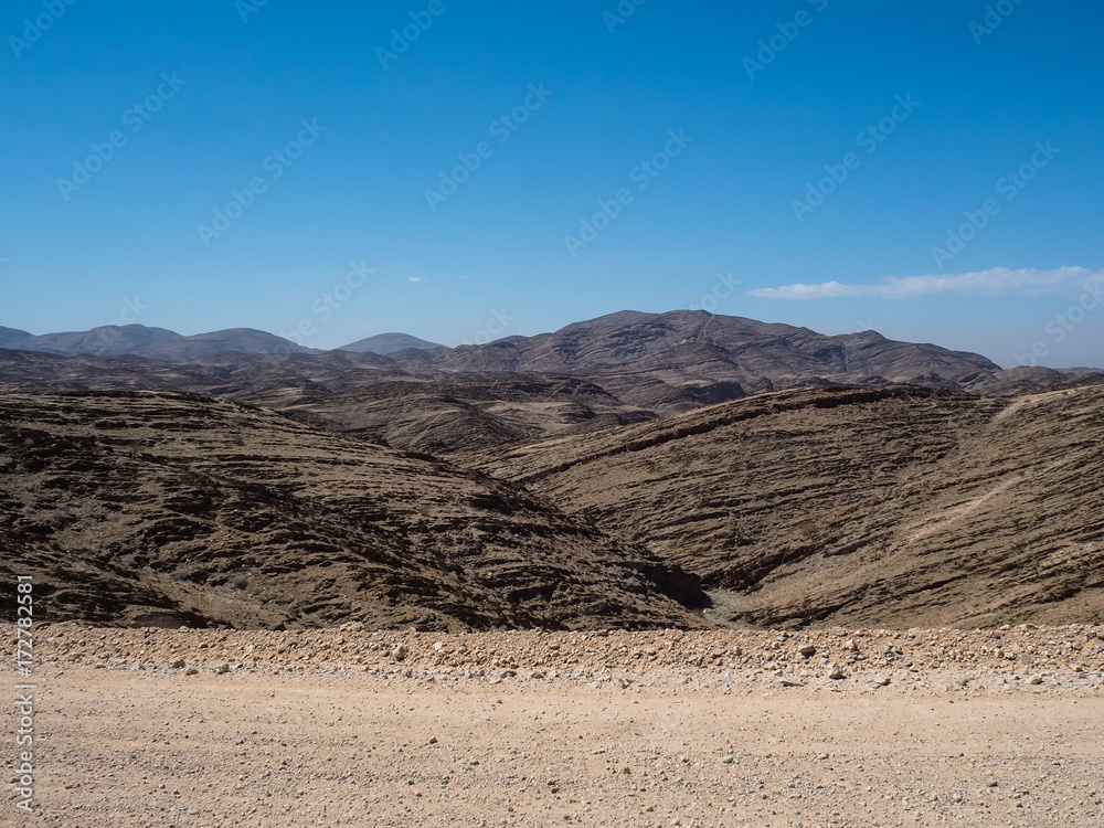Scene of great rock mountain texture layers panorama landscape view background and clear blue sky on unpaved dirt road