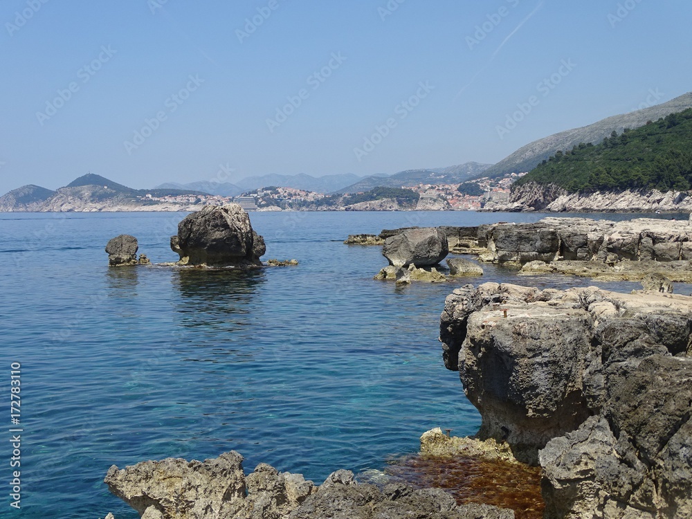 Rocky coast of the beach on the island Lokrum, on the Adriatic sea, with view of the medieval town of Dubrovnik in the background. Croatia.