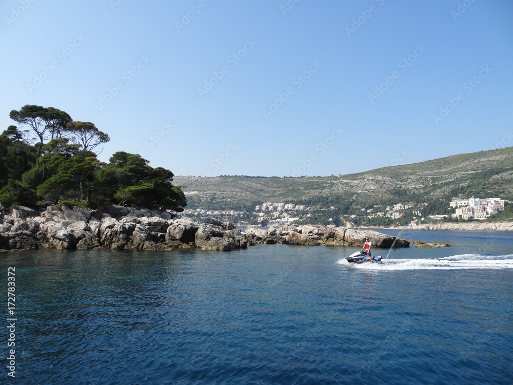 Navigation on the rocky coast of Lokrum Island and in the background the mountains of Dubrovnick in Croatia.
