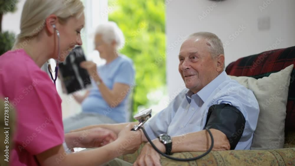 Young nurse checking elderly man's blood pressure in nursing home. Young nurse checking elderly man's blood pressure in nursing home.