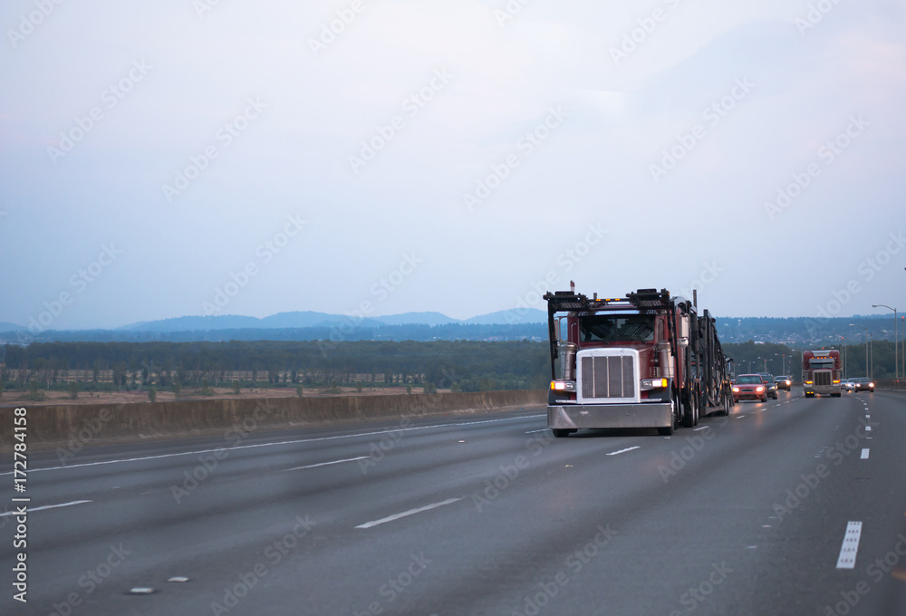 Big rig car hauler semi truck running in front of another traffic Big rig car hauler semi truck running in front of another traffic