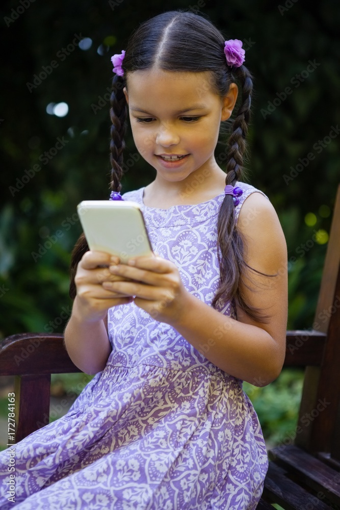 Girl using smartphone while sitting on bench