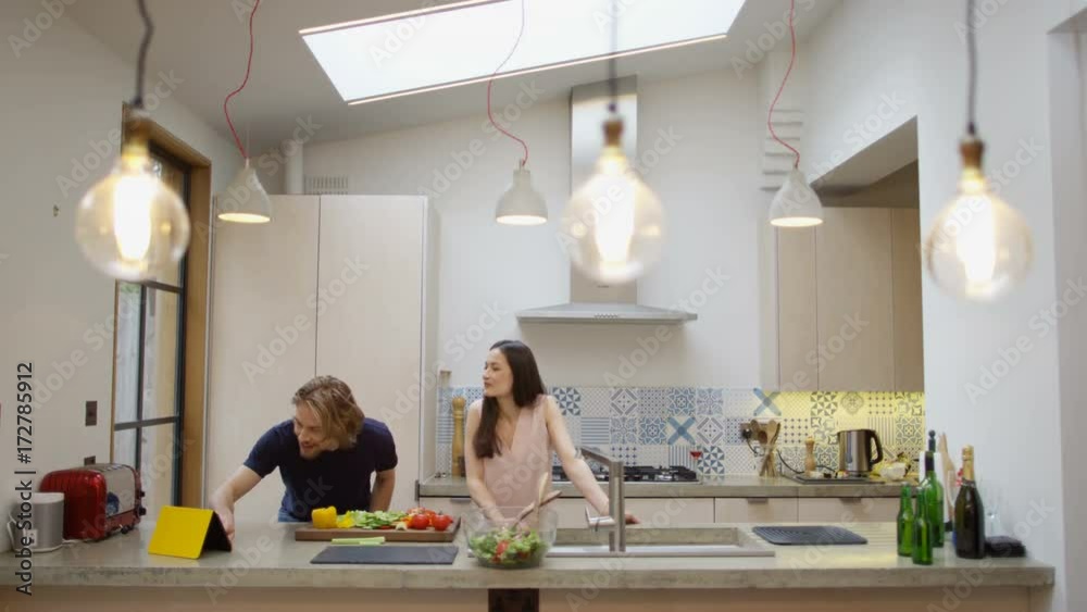 Happy affectionate couple dancing while they prepare a meal together in the kitchen at home. Happy affectionate couple dancing while they prepare a meal together in the kitchen at home.