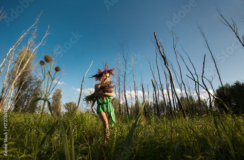 Girl, model in a wreath of flowers on a sunny day strolling in the woods in a meadow. Portrait, style, beauty, fashion.
