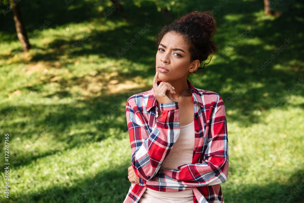 Thinking young african woman sitting outdoors in park. Thinking young african woman sitting outdoors in park.