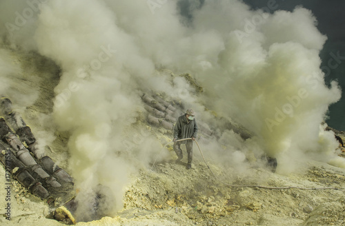 Kawah Ijen ranger trying to put of the smoke by spraying water from acid lake to enhance the sulphur production which is affected by flames and smoke, Indonesia
