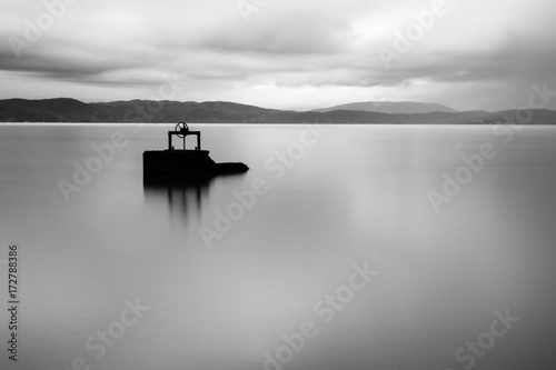 Long exposure view of a lake at dusk, with an old winch in the midst of water