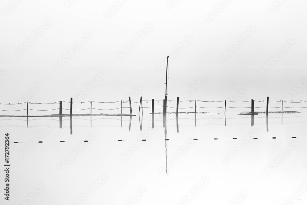 a flooded lake pier with water reflections in minimalistic black and white