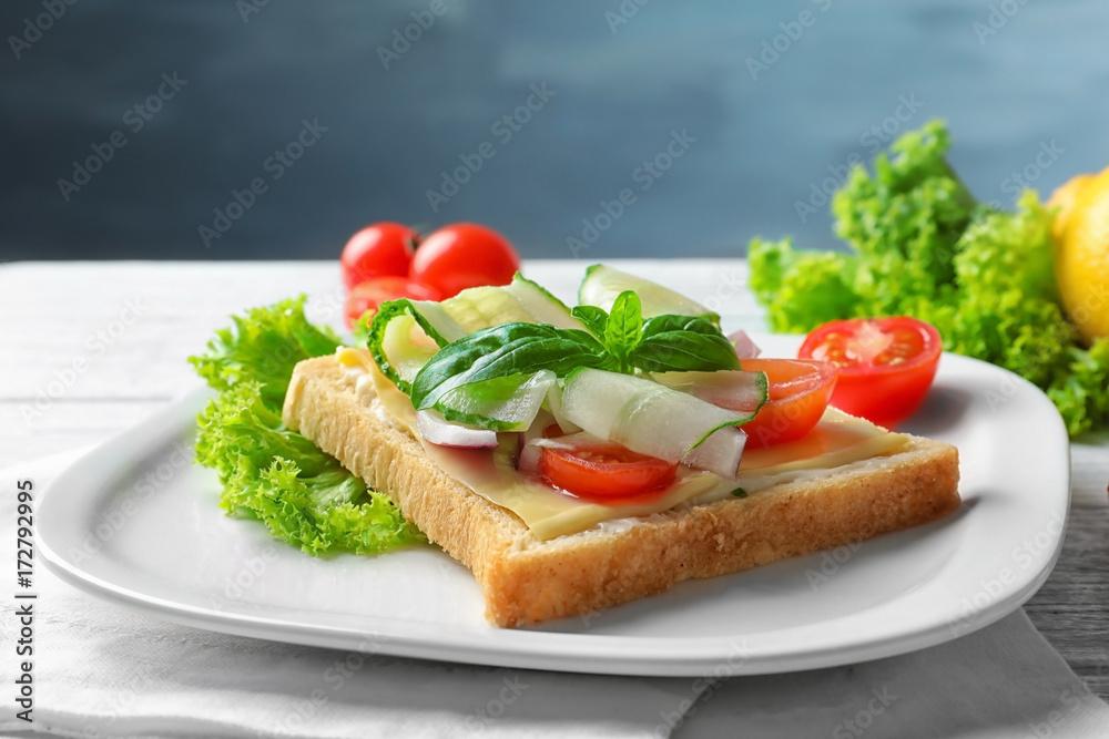 Plate of tasty sandwich with fresh cucumber on table