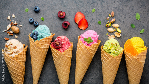 Photo Various of ice cream flavor in cones blueberry ,strawberry ,pistachio ,almond ,orange and cherry setup on dark stone background