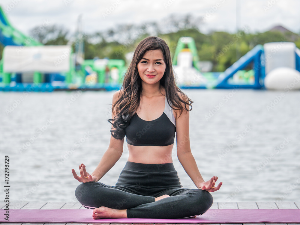 The acting setup of Yoga concept. A asian young woman doing Yoga outdoor by the lake.