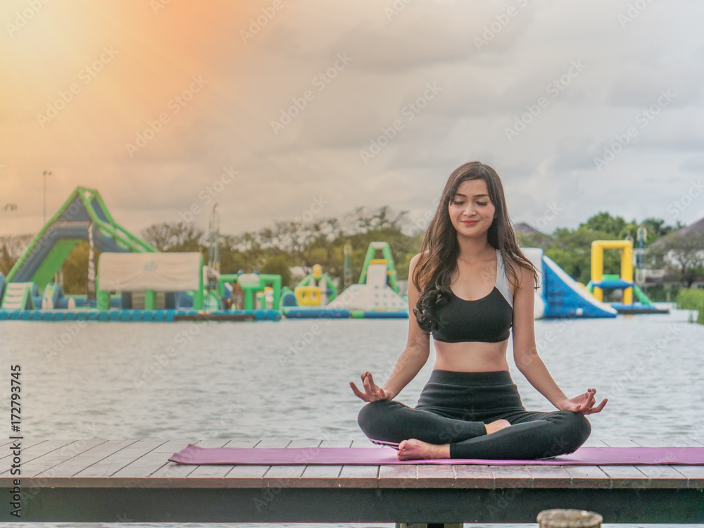 Fototapeta premium The acting setup of Yoga concept. A asian young woman doing Yoga outdoor by the lake.