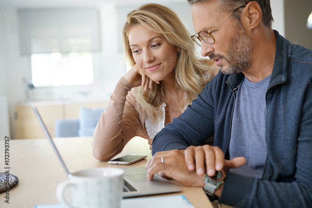Mature couple at home working on laptop computer Mature couple at home working on laptop computer