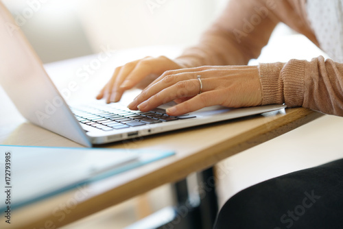 Closeup of woman's hands typing on laptop keyboard