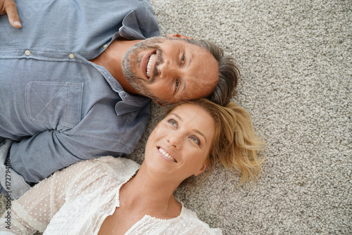 Upper view of cheerful couple laying on carpet