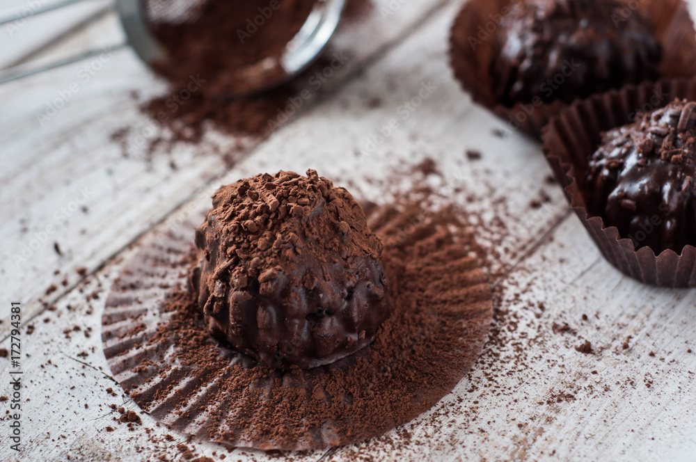 Chocolate chip muffin in brown wax paper. Unwrapped. Cocoa powder in the background Chocolate chip muffin in brown wax paper. Unwrapped. Cocoa powder in the background