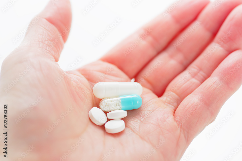 Blue capsule medicines and tablets in female hand. Prescription drugs. Concept image of medication.
Blue capsule medicines and tablets in female hand. Prescription drugs. Concept image of medication.