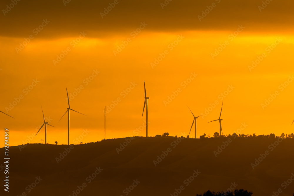 Obraz premium Wind turbines for electricity on a mountain at sunset.