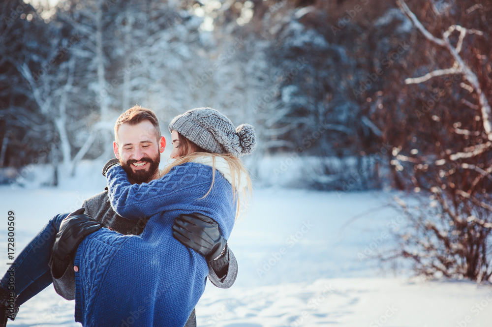 Obraz premium happy loving couple walking in snowy winter forest, spending christmas vacation together. Outdoor seasonal activities. Lifestyle capture.