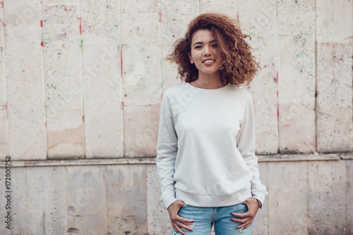 Curly haired girl with freckles in blank grey sweatshirt on the street. Mock up. photo