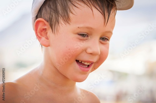Happy cute Caucasian boy sweating in the summer heat smiling at his parents.