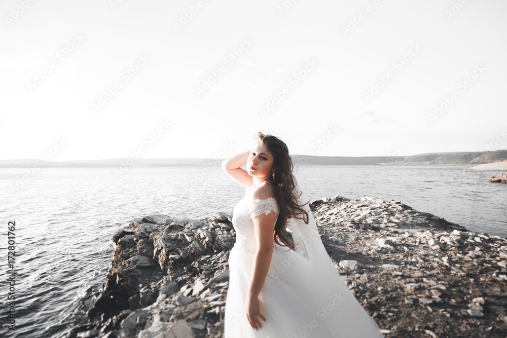 Romantic beautiful bride in white dress posing on the background sea Romantic beautiful bride in white dress posing on the background sea