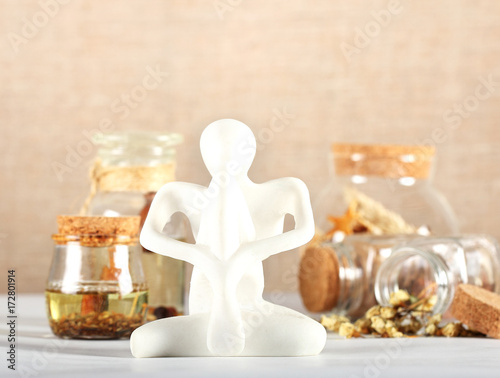 фигура йога стоит на столе рядом банки с травами 